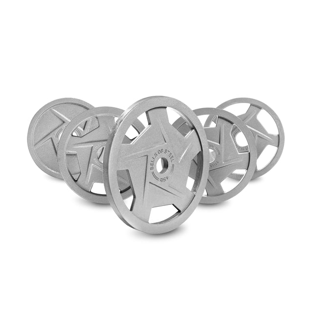 A set of four gray Mighty Grip Olympic Weight Plates by Bells of Steel, featuring a star-like design and a hammertone powder coating, stands upright in staggered formation. The nearest plate shows "BELLS OF" and "45 LB." The backdrop is plain white.