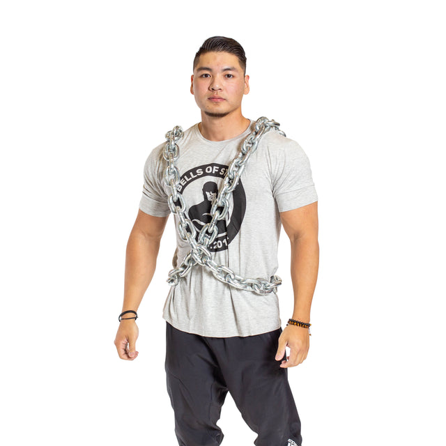 A man models the Bells of Steel Chain Weight Vest, draped over his shoulders and torso, wearing a light gray t-shirt and black pants against a plain white background—ideal for strength training visuals.