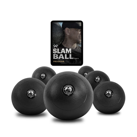 A semicircle of six black slam balls from the Wildman Slam Program Large Bundle by Bells of Steel is arranged for action, with a tablet in the background subtly displaying the program cover, suggesting high-intensity training designed to enhance muscular endurance.
