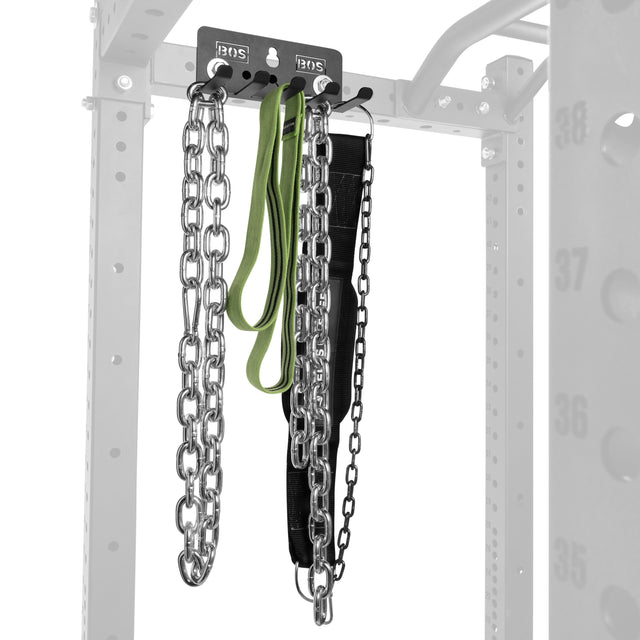 The Bells of Steel Accessory Holder (Wall or Rack Mounted) neatly stores two heavy chains, a green resistance band, and a black weightlifting belt on hooks, with part of the rack frame visible in the background.