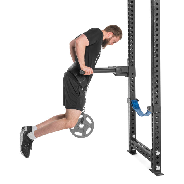 Wearing black athletic clothes, a man uses a Bells of Steel Dip Belt with a weight plate for weighted dips on parallel bars—a prime example of advanced bodyweight exercise.