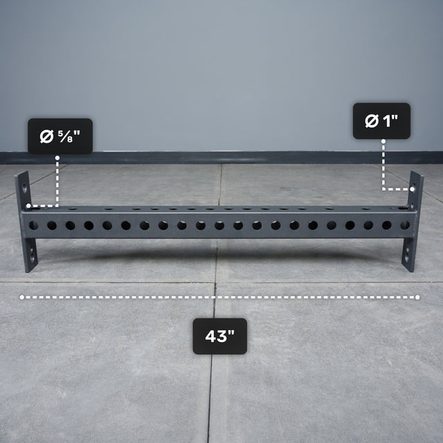 The Bells of Steel Crossmember For Converter Bench - 43" is a black metal bar with evenly spaced 5/8" and 1" holes, shown on a gray floor—perfect for rack setups or converter bench projects.
