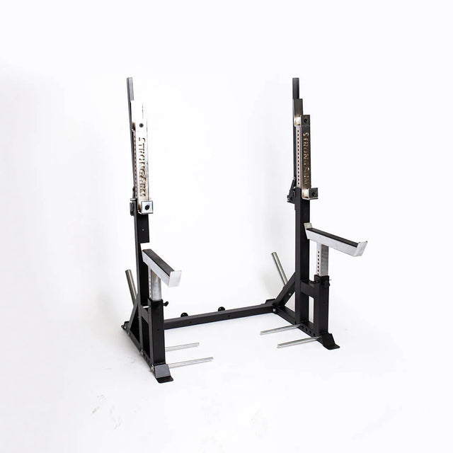 The Bells of Steel StrongArm Combo Rack is a black adjustable squat and bench press stand with safety arms, weight plate holders, and numbered height settings, shown against a plain white background.