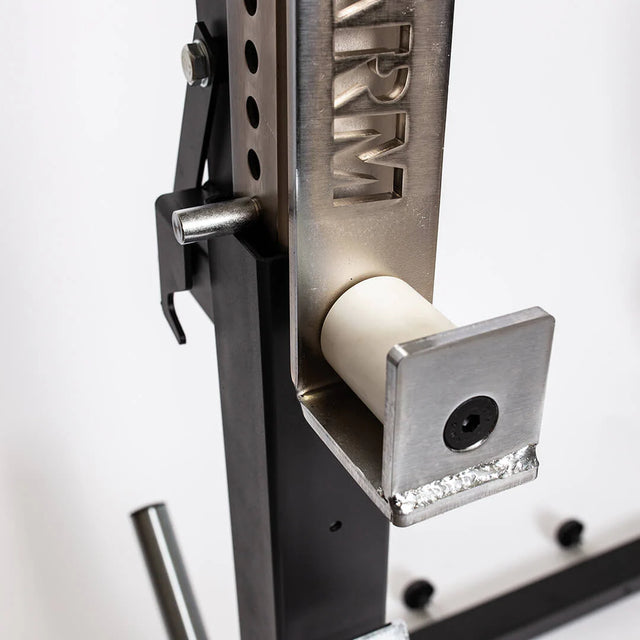 Close-up of a metal component from the Bells of Steel StrongArm Combo Rack - Squat Stand & Bench Press, showing a textured steel post, adjustable pin, and horizontal roller on a bracket, set against a white background.