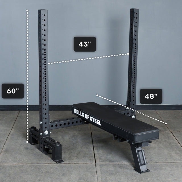 The Bells of Steel Hydra Two Post Converter Bench, 48" long and black with branding on the side, sits in a two-post squat rack measuring 60" tall and 43" wide between uprights.
