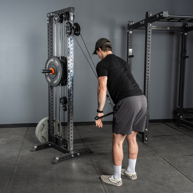 A man in athletic clothing uses the Bells of Steel Flat-Iron Tricep Press Cable Attachment at the gym, standing and pulling both handles down to perform a triceps exercise for optimal muscle activation.