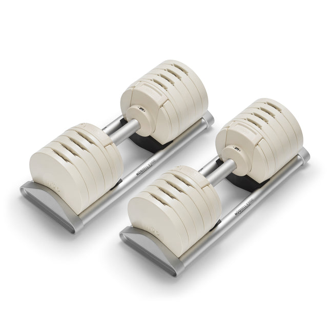 The Bells of Steel NÜOBELL-S Adjustable Dumbbells feature off-white rectangular plates and silver handles, resting on matching trays—precision-engineered to elevate any home gym setup.