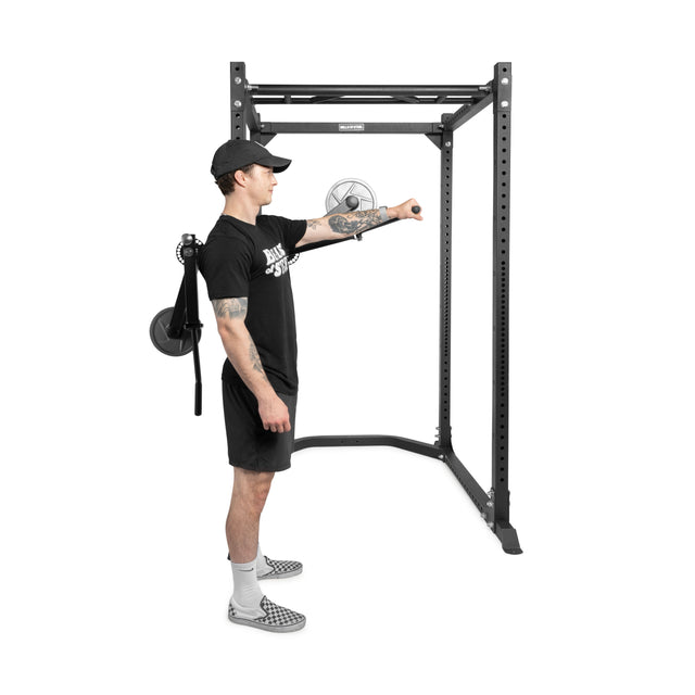 A man in athletic wear uses the Bells of Steel Shoulder Boulder/Chest Fly Attachment, extending one arm forward while standing sideways to the equipment to isolate his shoulder and chest muscles.