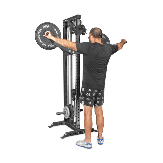 A person uses the Bells of Steel Shoulder Boulder/Chest Fly Attachment, extending their arms out to the sides while performing a strength exercise.