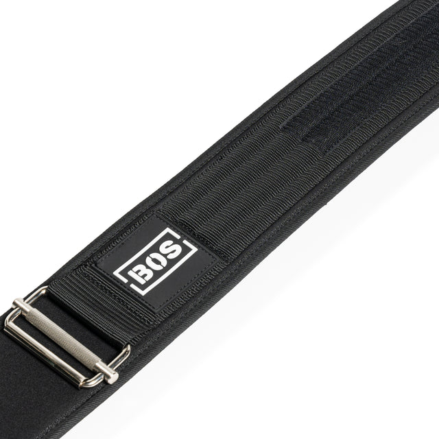 A close-up of the Bells of Steel Self Locking Belt shows its black adjustable strap, metal buckle, reinforced stitching, Velcro strip for security, and a rectangular BOS logo patch—ideal as a self-locking belt or for back support.