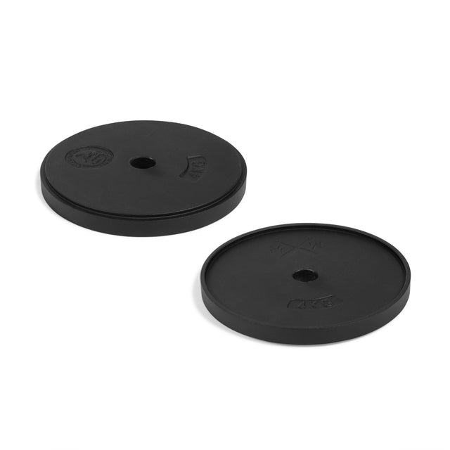 Two black, round weight plates marked “10 kg” and “4 kg” from Bells of Steel's 48KG Extension Kit for Adjustable Kettlebell "Wildman Poison Pill" sit on a white surface, ideal for upgrading or expanding your heavy kettlebell set.