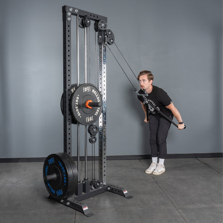 Wearing workout clothes, a person uses the Bells of Steel Extra Long Tricep Rope Extension (137cm) for tricep pushdowns, standing on a gym floor against a gray wall.