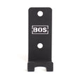 The Bells of Steel Hanging Barbell Holders are black, rectangular metal mounts labeled "BOS," featuring two mounting holes and a lower lip to securely store your barbells in your lifting gallery.