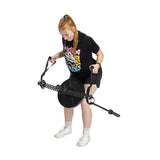 A red-haired woman in a ponytail uses the Bells of Steel 30 D-Handle Bar Cable Attachment with Carabiners. She wears a black t-shirt with a colorful design, black shorts, and white sneakers, standing against a white background.