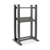 The Hydra Flat Foot Components by Bells of Steel is a gray metal rack that acts as a power rack, offering multiple adjustable settings. It features a rectangular base with flat foot support, two vertical supports, and a top bar with a central shelf. Ideal for weightlifting and gym use.