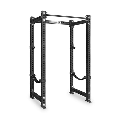 The Bells of Steel Manticore Four Post Power Rack Builder (3" x 3", 1" Holes) is a black metal, freestanding power rack featuring adjustable safety straps, multiple attachment holes, and an integrated pull-up bar on top. Perfect for weightlifting and strength training, this sturdy rack stands on a white background and is ideal for any home gym setup.