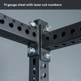 Close-up of black steel beams from the Bells of Steel Manticore Four Post Power Rack – Prebuilt (3" x 3", 1" Holes), featuring laser-cut numbered holes and large silver bolts at the intersections. Text above reads, “11 gauge steel with laser cut numbers.” This modular rack delivers a durable, customizable foundation engineered for strength in your home gym.