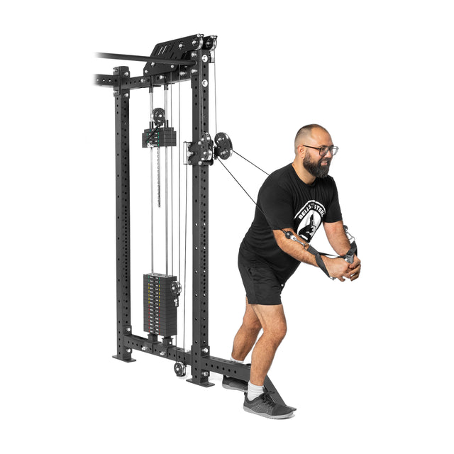 Wearing a black t-shirt, shorts, and gray shoes, a person works out in an isolated environment with the Kraken Rack Attachment for 4 Post Hydra & Manticore Racks by Bells of Steel, pulling cables towards their chest using the dual-handle cable tower.