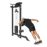 A person uses a Bells of Steel Kraken Rack Attachment for 4 Post Hydra & Manticore Racks (Single Side), leaning forward to pull a rope attachment. They're dressed in a black shirt, black shorts, white socks, and black shoes.