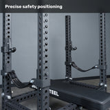 A close-up of the Bells of Steel Manticore Four Post Converter Bench inside a power rack shows adjustable safety straps and multiple numbered holes. The text "Precise safety positioning" appears at the top.