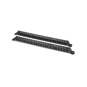 The Manticore Flat Foot Components by Bells of Steel are two black metal brackets with multiple holes for adjustable installation, designed to complement the Manticore power racks. Placed parallel on a white surface, they offer enhanced stability and versatility.