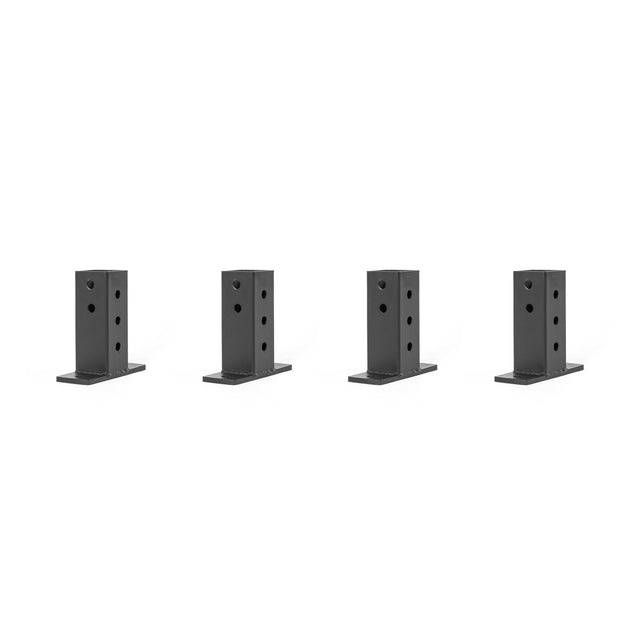 Four black, rectangular metal brackets with multiple holes, likely used as wall connectors for Hydra & Manticore racks from Bells of Steel, are arranged in a row against a plain white background.