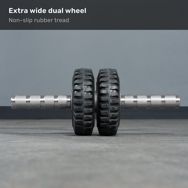 The Bells of Steel ABsyidyan Stainless Steel Ab Roller features an extra-wide dual wheel, non-slip rubber tread, knurled metal handles, and supports up to 500 lbs. Displayed resting on a gray floor.