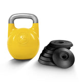 A yellow Bells of Steel Adjustable Competition Kettlebell with a silver handle and circular front logo is placed beside black weight plates on a white background, perfect for kettlebell training.