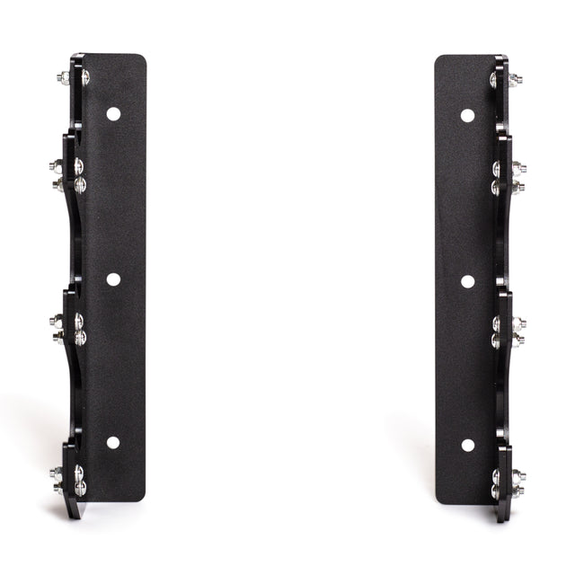 Against a plain white background, two brackets from the Bells of Steel 3 Barbell Wall Rack in black metal stand upright. Designed for optimal wall-mounted barbell storage, each bracket showcases multiple screws and alternating curved edges that create a symmetrical design.