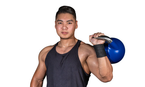 A muscular man sports Bells of Steel wrist wraps and a sleeveless black tank top while confidently holding a blue kettlebell over his shoulder, posing against a plain white background.