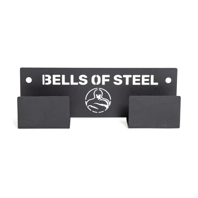 A sleek, black metal wall-mounted sign artfully displays the "Bells of Steel" brand name along with a weightlifter logo. Known as the Wall or Rack Mounted Bench Hanger, this product includes flat, rectangular hooks that are ideal for organizing gym equipment or accessories while also serving as a stylish bench hanger.