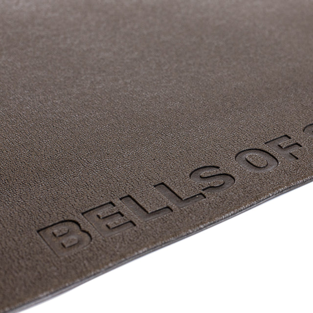 A close-up of a textured brown Bells of Steel Cardio Machine Floor Mat, with the embossed brand name partially visible near the edge.
