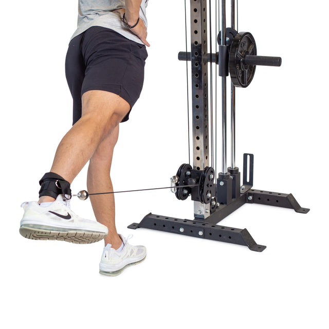 Using the Bells of Steel Adjustable Ankle Strap Cable Attachment - Pair, a person focuses on glute-training with a cable machine, stretching one leg backward for excellent stability and range of motion.