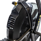 Close-up of the black Bells of Steel Blitz Max Air Bike fan with a protective cover and part of the pedal visible. This commercial air bike features bold yellow "BLITZ" branding, making it perfect for any fitness studio equipment lineup.