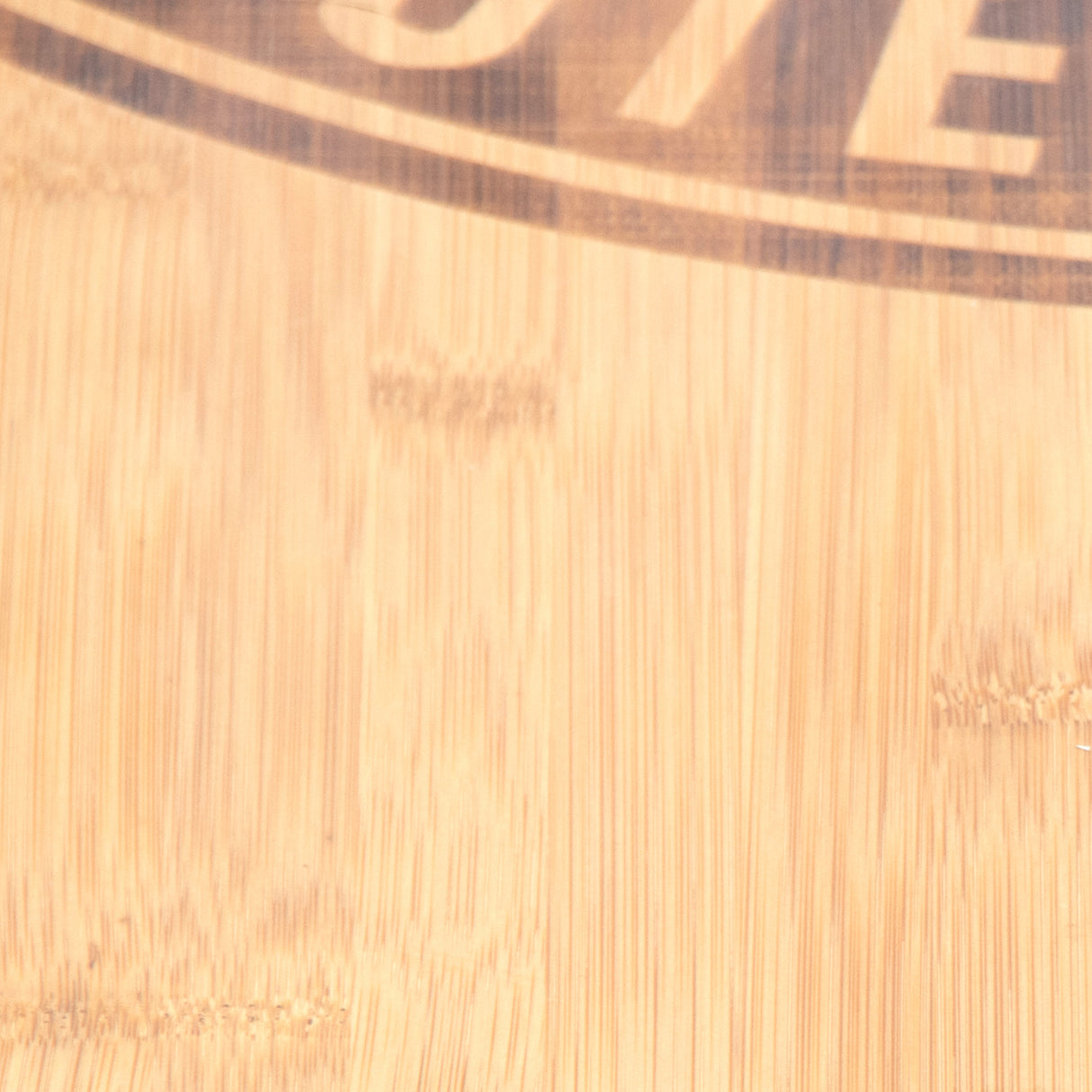 Close-up image of a light bamboo surface from the Deadlift Platform Bamboo Insert (Right) by Bells of Steel, featuring visible wood grain with partial and indistinct circular logo or text.