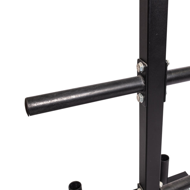 A close-up shows a metal bracket from the Bells of Steel Bumper Plate Weight Tree and Bar Holder, attached to a vertical post with a horizontal handlebar. Black metal parts are bolted together against a plain white background, resembling gym equipment's bar storage system.