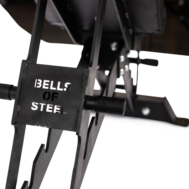 The black metal weight rack with "BELLS OF STEEL" cut-out is paired with the Buzz-Saw Heavy-Duty Adjustable Bench. Perfect for any exercise routine, the sturdy rack features various hooks and attachments against a clean white background.