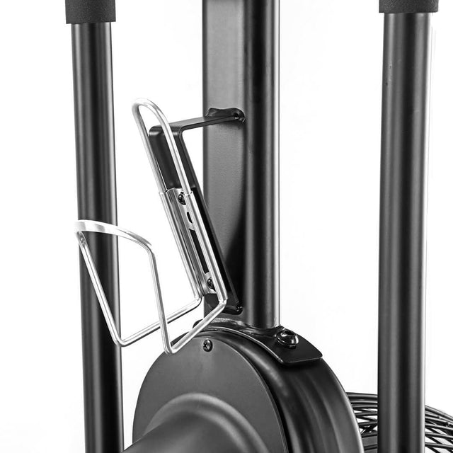 A close-up of the Bells of Steel Blitz Air Bike, ideal for a full-body workout in your home gym, showcases its sleek black design with a silver metal bottle holder. Visible vertical bars and a fan-like component at the base enhance its robust appeal.