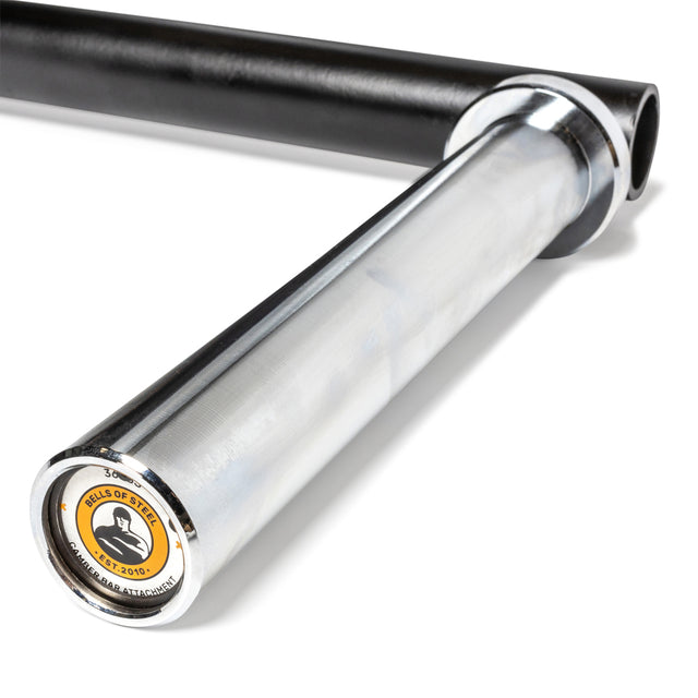 A close-up of the Bells of Steel Camber Bar Attachment showcases its sleek silver metal design with a black sleeve and secure barbell collars. The end features a circular logo depicting a stylized weightlifting figure and text, all set against a white background to accentuate its modern aesthetic.