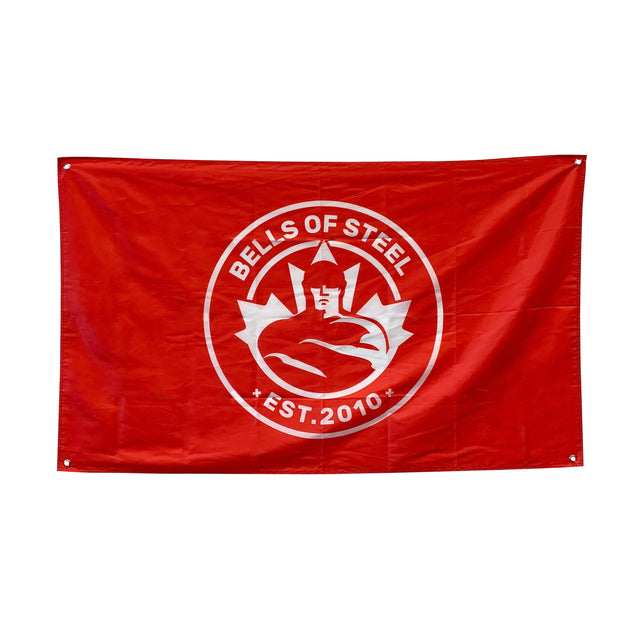 This eye-catching gym flag from Bells of Steel features a bold red background, highlighting a white circular logo depicting a muscular figure lifting a barbell. The words "Bells of Steel" appear prominently above the design, with "Est. 2010" below it, making it perfect for any home gym setting. It comes with four corner grommets for convenient hanging and display.