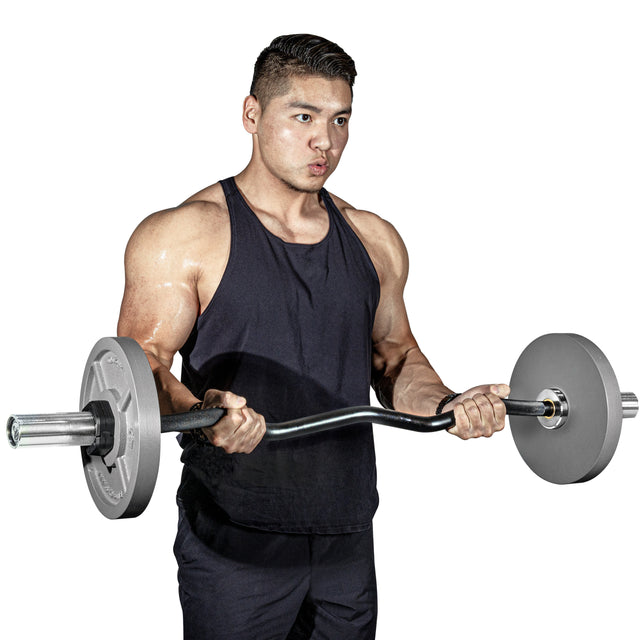 A muscular man in a black tank top lifts a barbell fitted with Bells of Steel Machined Iron Olympic Weight Plates, executing a bicep curl. He stands against a plain white background, focusing intently on his exercise.