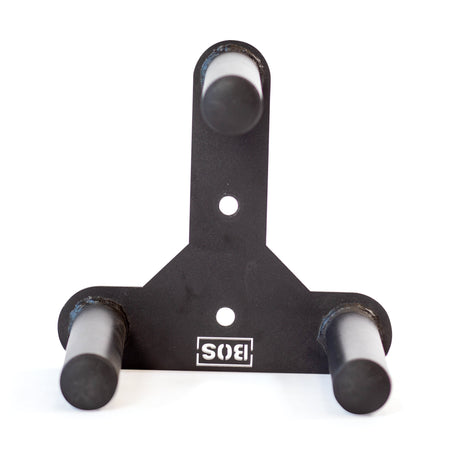 The Bells of Steel Change Plate Storage Pegs is a black wall-mounted holder with three forward-facing, metallic cylindrical prongs. The rectangular base displays the logo in white, ideal for efficiently organizing change plates.