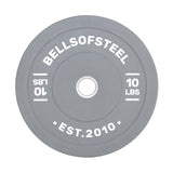 The gray Coloured Bumper Plate by Bells of Steel features "BELLSOFSTEEL" and "EST. 2010" in bold white text, an accurate weight, a durable stainless steel insert, and "10 LBS" marked on both sides around the center hole.