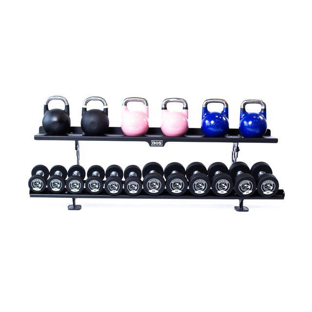 The Bells of Steel Commercial Interchangeable Weight Rack features a swappable top shelf holding black, pink, and blue competition kettlebells above a row of white-marked commercial urethane dumbbells, all on a white background.
