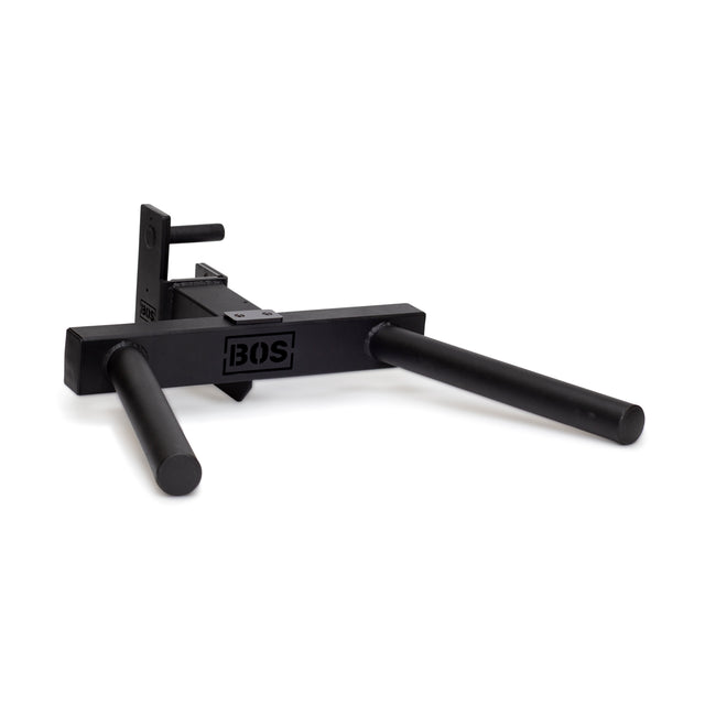 The Y Dip Bar Rack Attachment by Bells of Steel is a robust black metal dip station featuring tubular handles. It is designed to attach effortlessly to gym equipment racks, boasting a compact and sturdy build for enhanced durability. The brand name "Bells of Steel" is prominently displayed on the side.