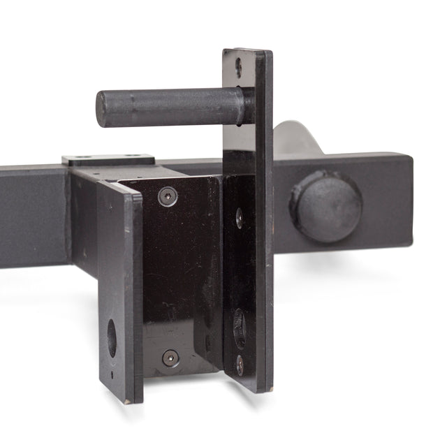 Close-up of the Y Dip Bar Rack Attachment by Bells of Steel featuring a heavy-duty black metal construction with a pin lock, designed for secure mounting. The image highlights the mechanism with a protruding cylindrical pin and multiple mounting holes, emphasizing its sturdy build—perfect for rack attachment.