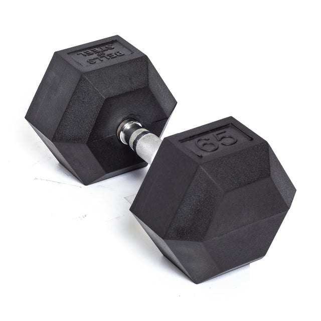 A Bells of Steel Ergo Rubber Hex Dumbbell, weighing 65 lbs, rests on a white surface. It features a black rubber coating and a metallic handle with an ergonomic, textured grip for optimal comfort.