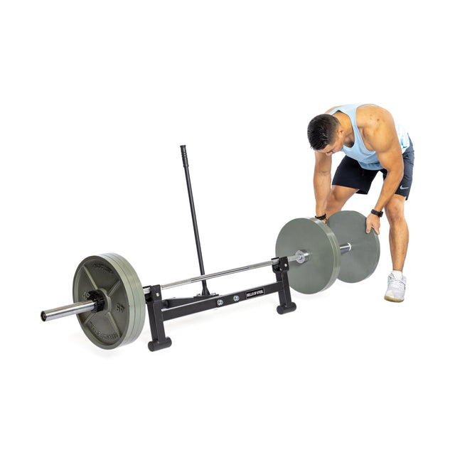 Dressed in athletic wear, someone adjusts weights on a barbell set on the Bells of Steel Deadlift Jack with Rollers against a plain white background.