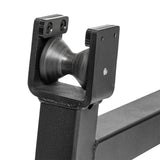 Close-up of a black metal bracket featuring a spinning, cone-shaped nylon roller in the center, mounted on a square tube structure. Similar to the Deadlift Jack with Rollers by Bells of Steel, the roller gives an impression of motion with its blur effect.