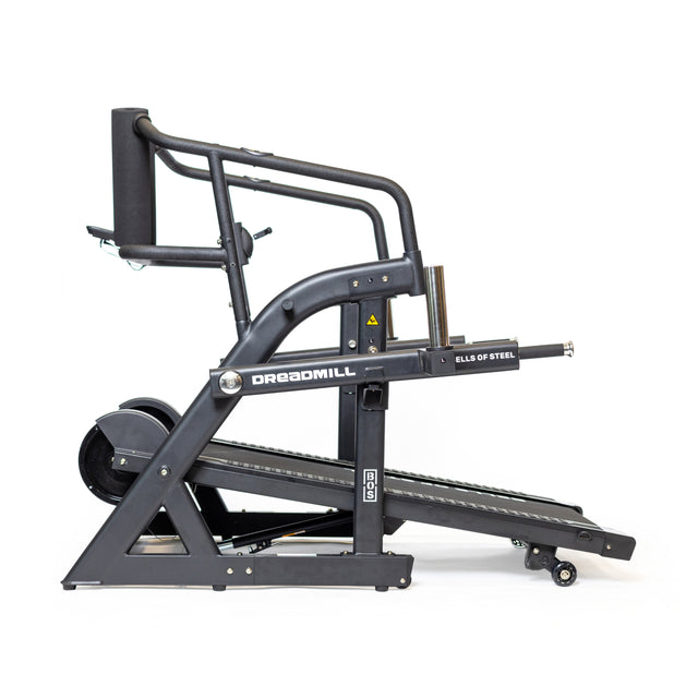 Side view of The Dreadmill by Bells of Steel, featuring a sleek black design with a slanted running surface, handlebars, and manual incline. Set against a white background, it highlights the magnetic resistance lever for enhanced workouts.